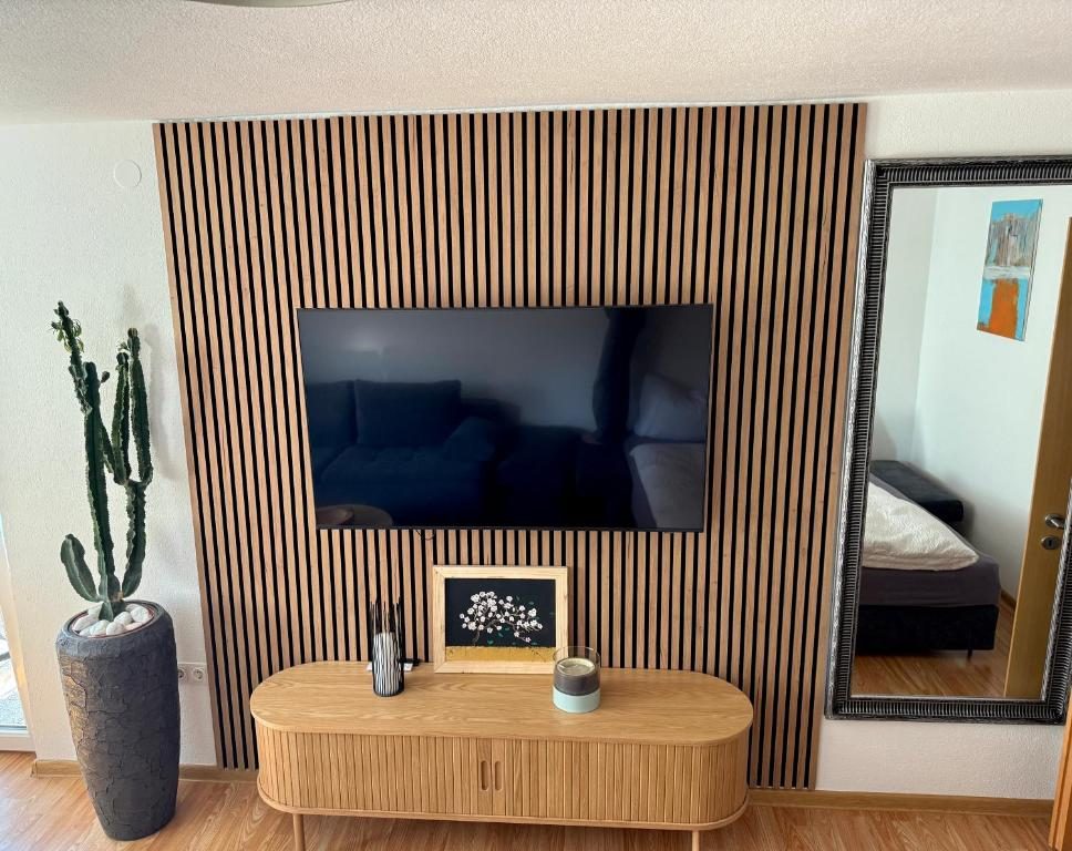 Wohnzimmer mit Holzlamellenwand und Flachbild-TV